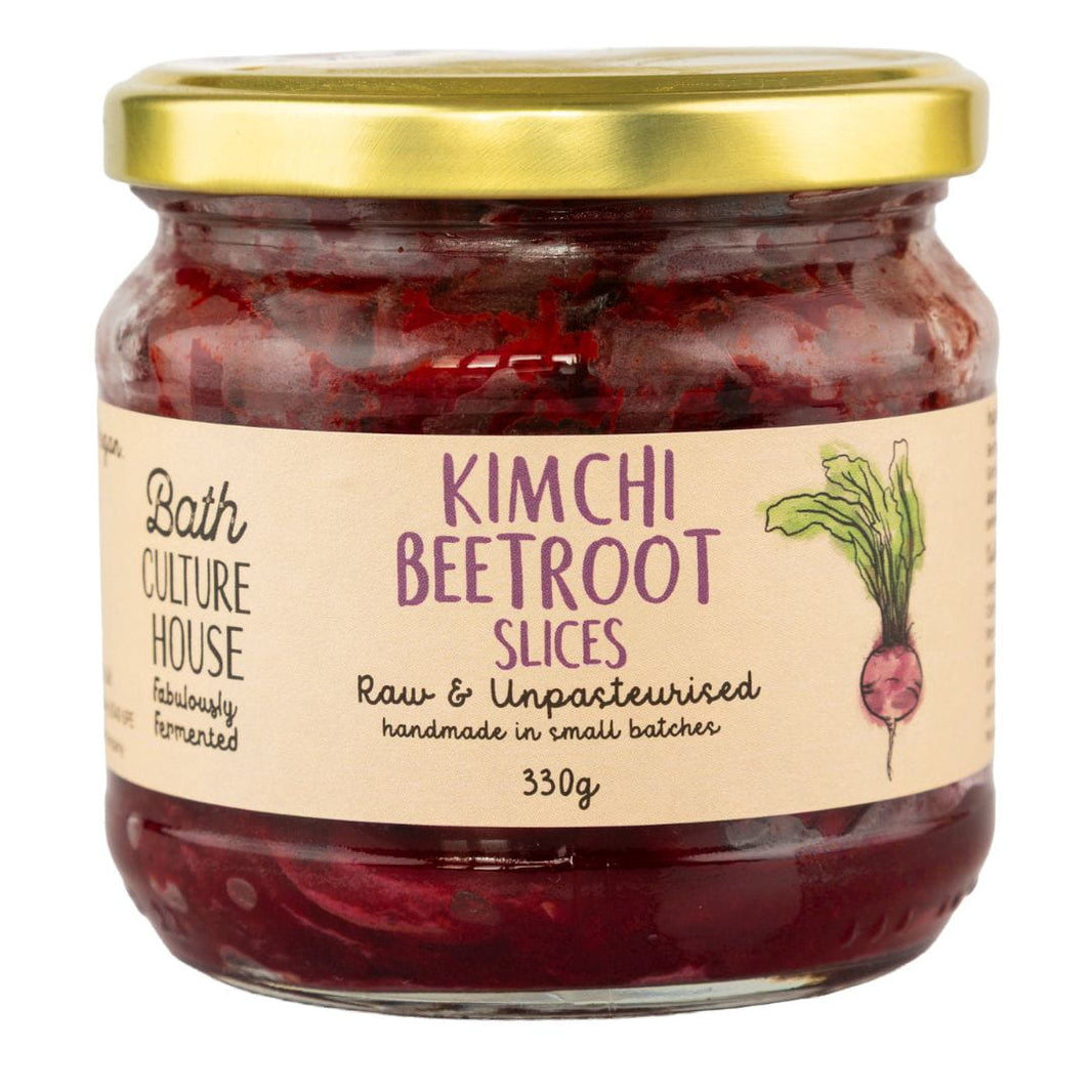 Jar of kimchi beetroot slices with a gold lid on a white background