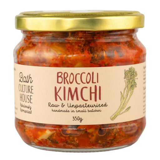 Jar of broccoli kimchi with a gold lid and label on a white background