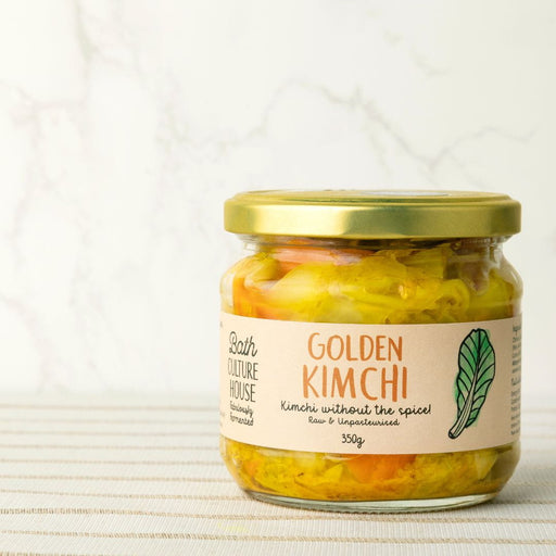 Jar of Golden Kimchi with a gold lid on a textured white background