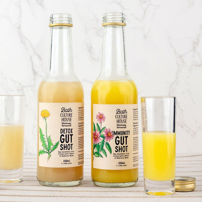 Two bottles of Bath Culture House gut shots with glasses on a white background. Pickle juice