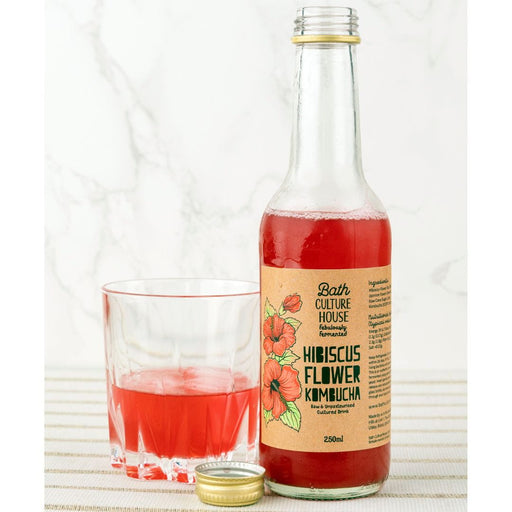 Hibiscus flavoured kombucha next to a glass on tablecloth