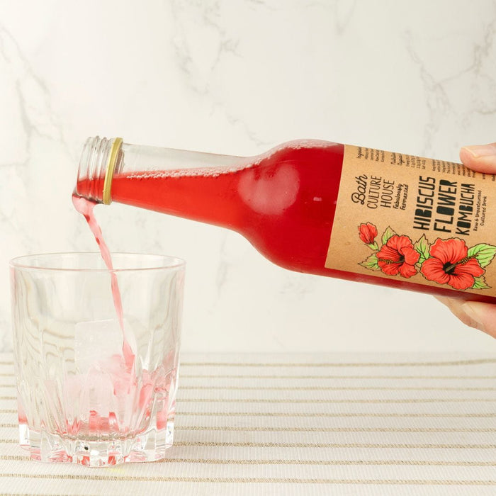 Bottle of raw and unpasteurised kombucha being poured by hand