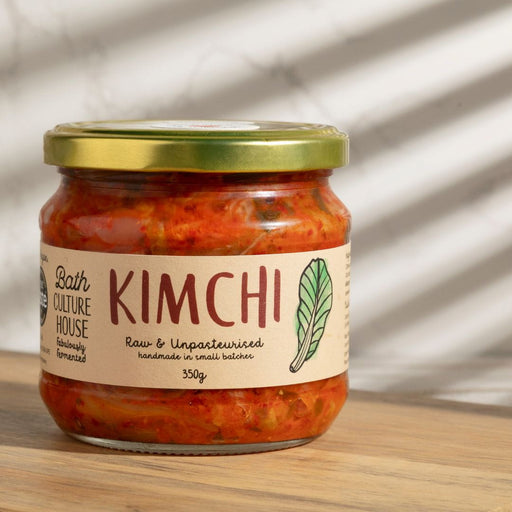 Jar of kimchi with a gold lid on a wooden surface