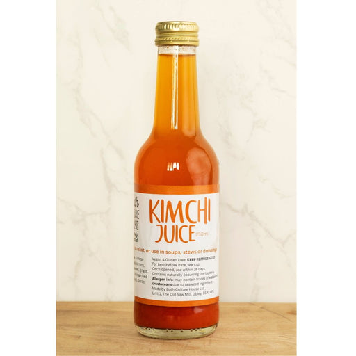 Bottle of kimchi juice on a wooden surface with a white background