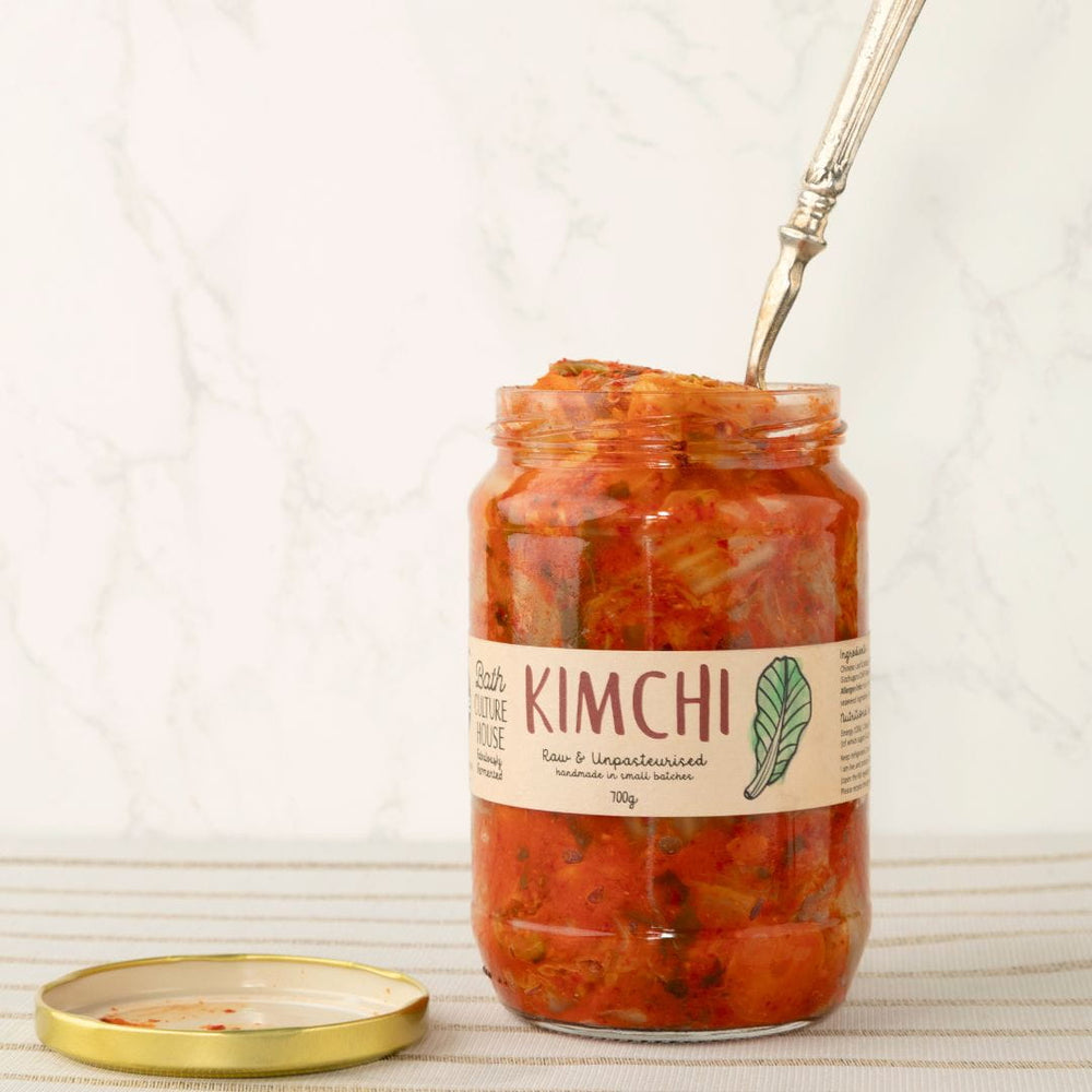 Jar of kimchi with a fork inside, on a light background