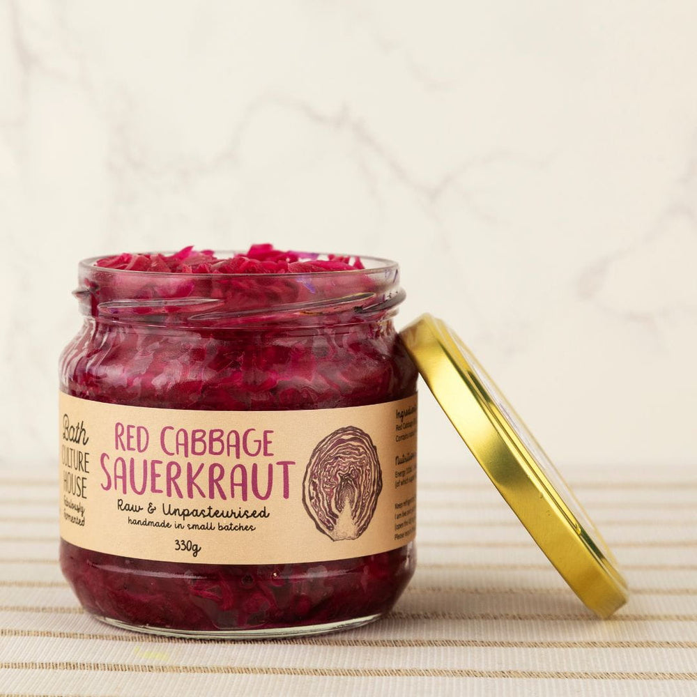 Jar of red cabbage sauerkraut with a gold lid on a textured surface