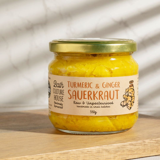 Jar of Turmeric & Ginger Sauerkraut from Bath Culture House on a wooden surface with a blurred background