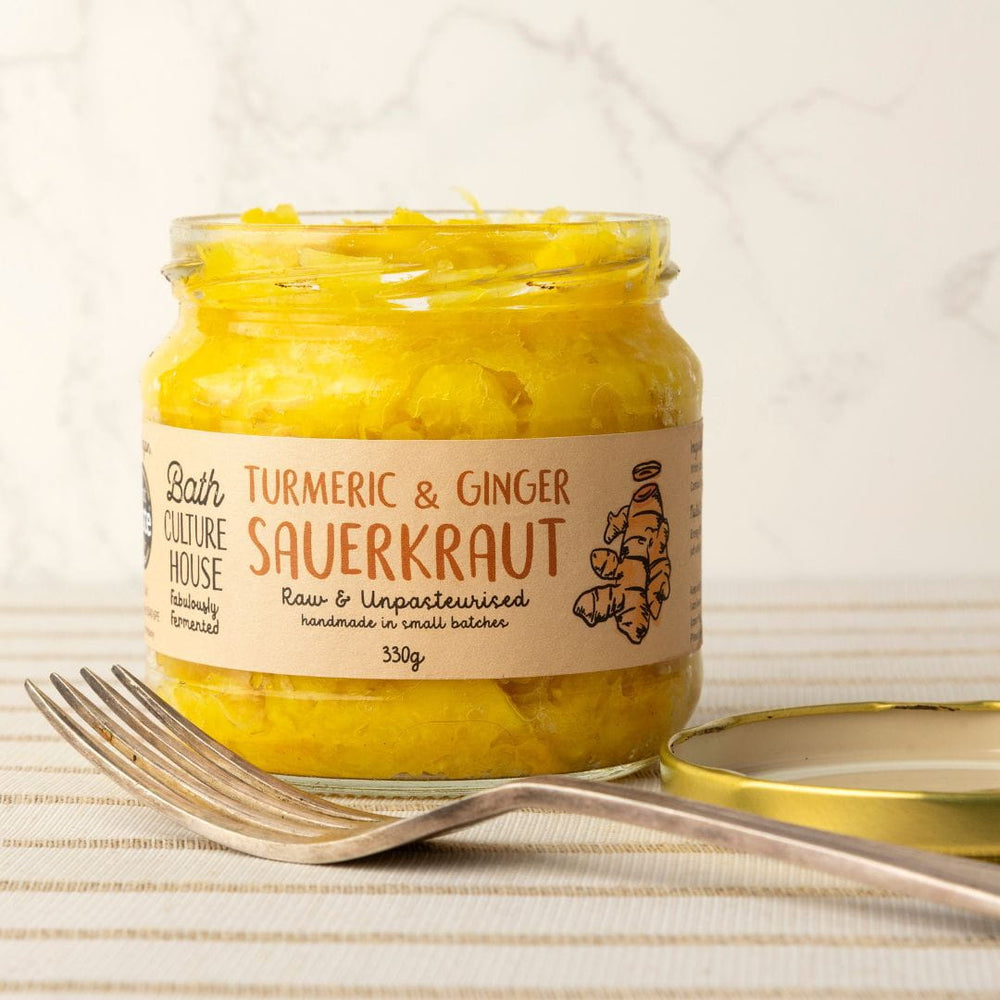 Jar of Turmeric & Ginger Sauerkraut with a label on a textured surface.